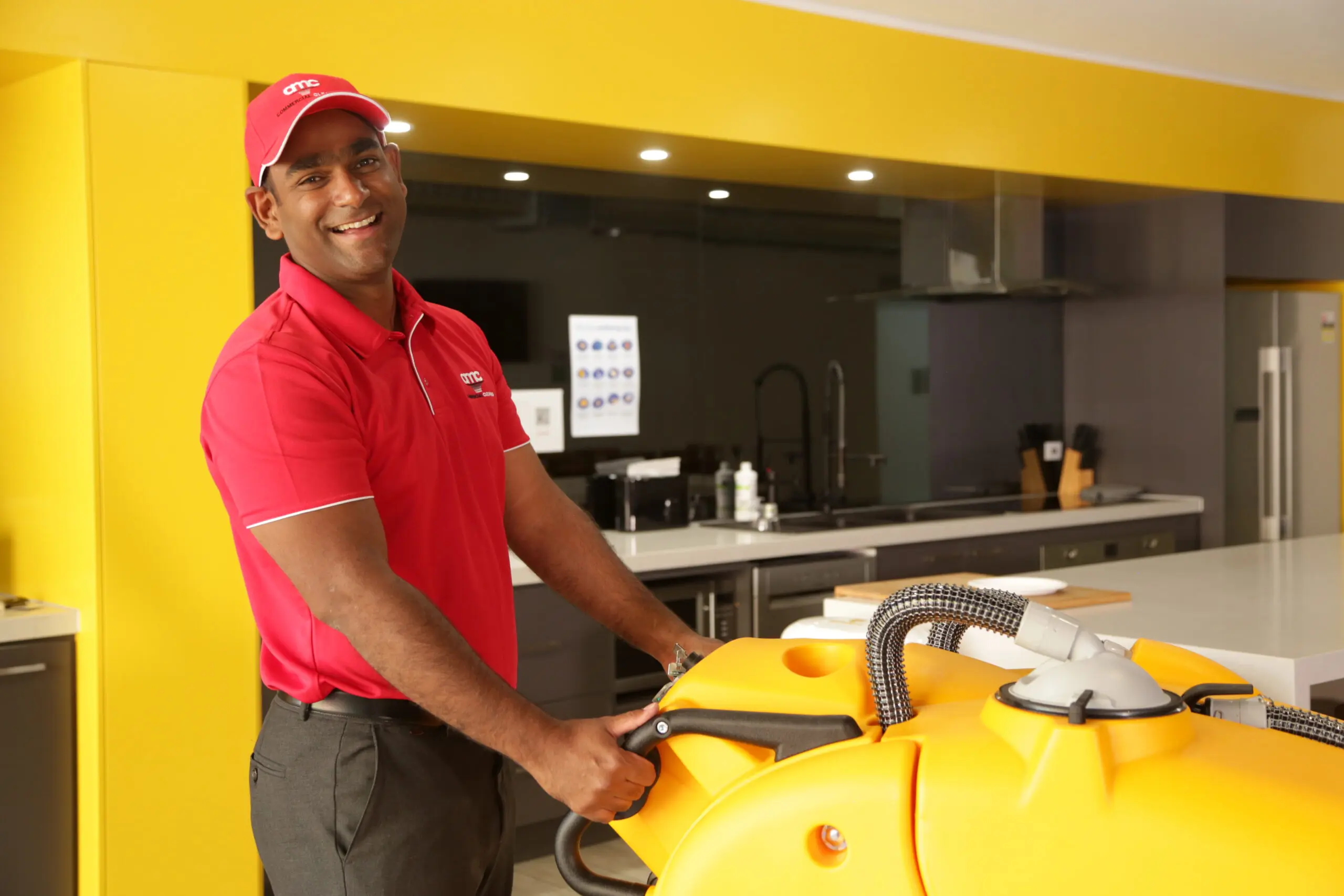 Cleaner using a walk behind cleaning machine to clean a large industrial floor