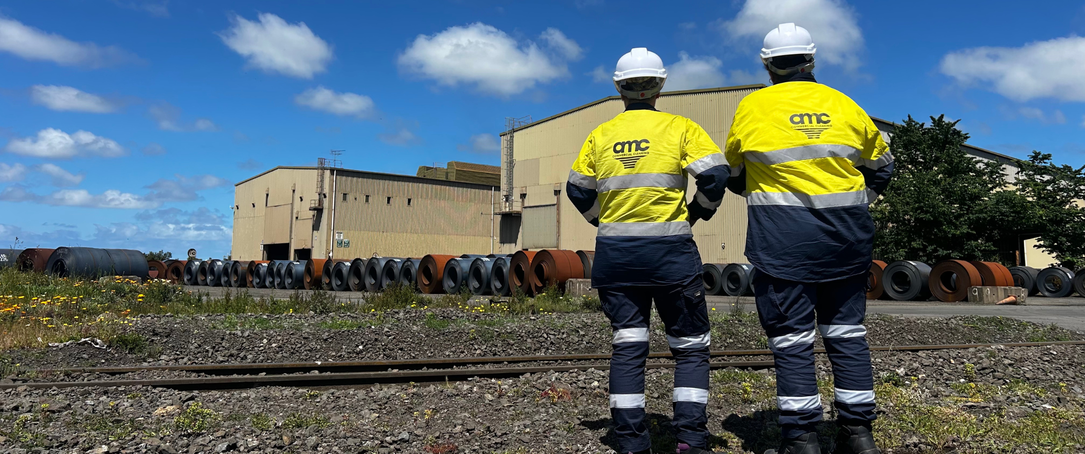 cleaners in PPE at large steel industrial site
