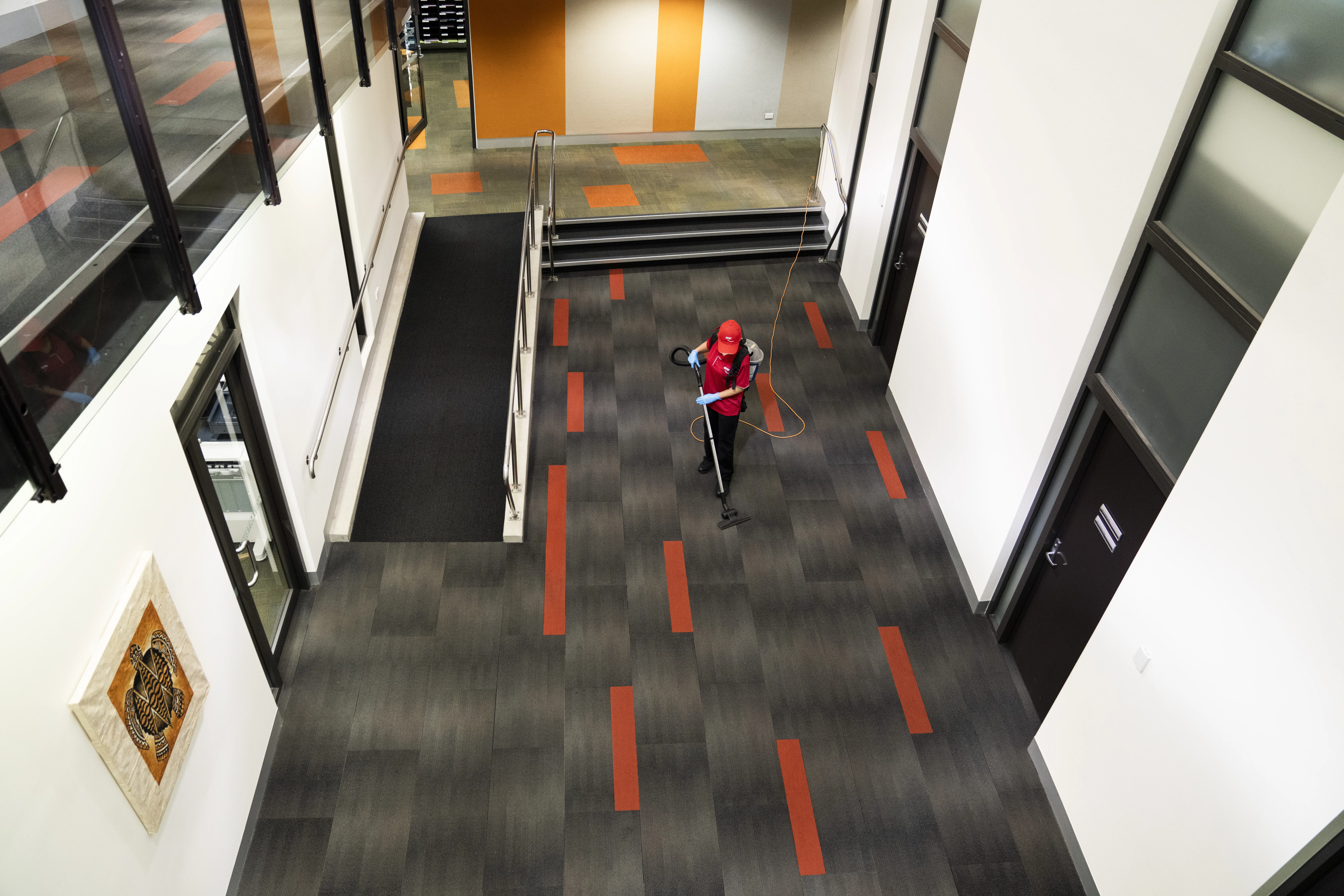 Cleaner vacuuming open-plan office during quiet occupancy period within Hybrid Workplace Cleaning schedules